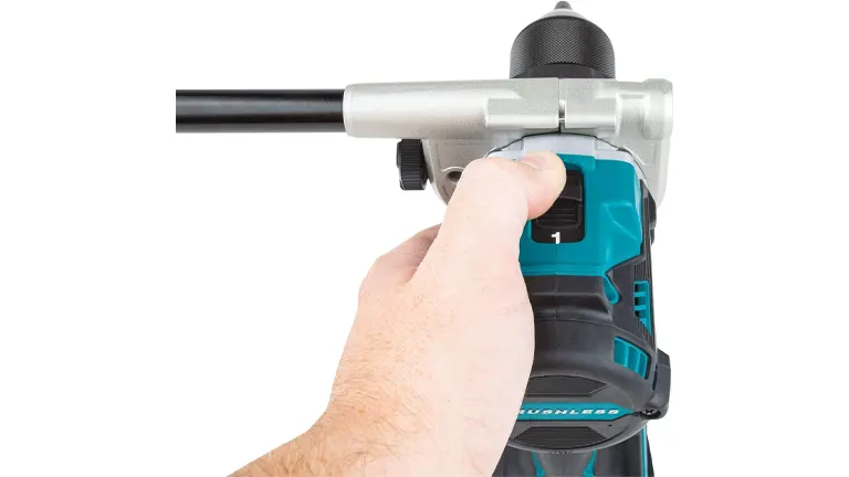 A close-up of a person's hand gripping the handle of a Makita cordless hammer drill, highlighting the tool's trigger and ergonomic design.