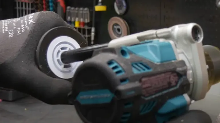 A Makita cordless hammer drill is in focus against a blurred workshop background, with a drill bit inserted and ready for use.