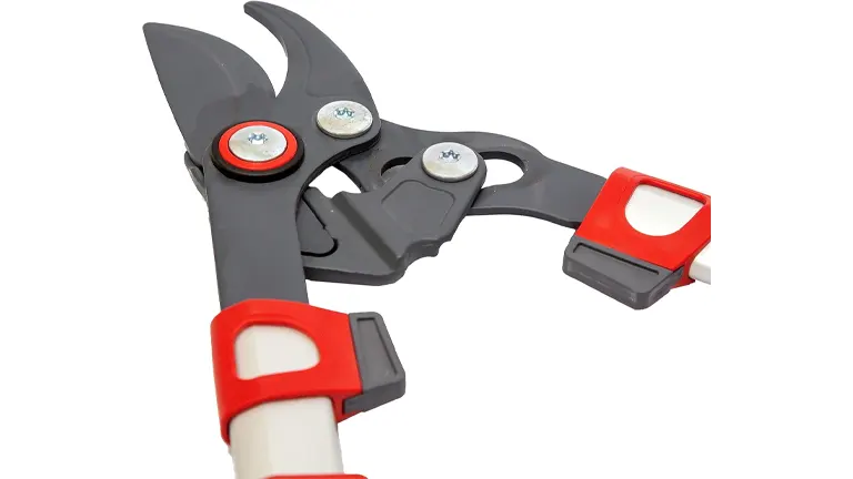 A close-up of a bypass lopper's cutting head, with a black blade and red and grey handles, featuring an open safety lock.