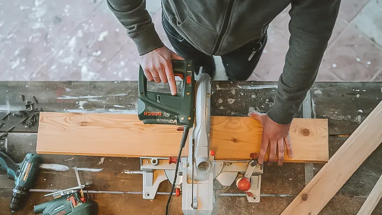 Person using a circular saw to cut a wooden plank on a workbench