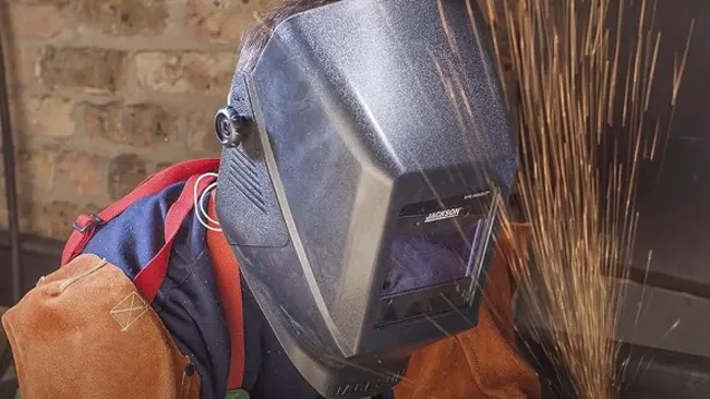 Worker wearing a Jackson Safety W40 Insight WH 40 welding helmet with visible sparks from welding.







