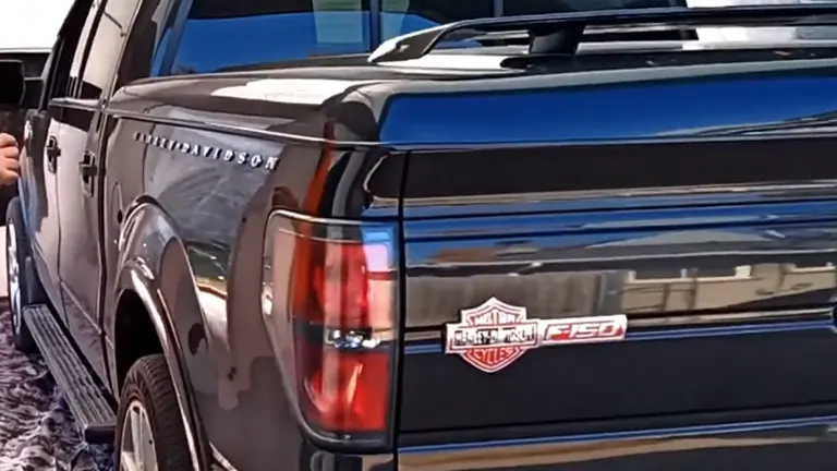 The image features a close-up view of the tailgate and rear light of a dark-colored Ford F-150 truck, highlighting the Harley-Davidson edition badge.