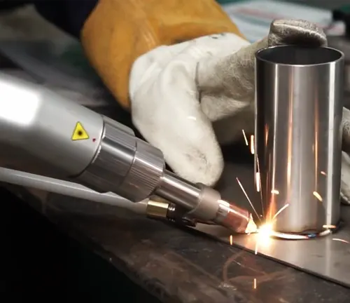 Gloved hand operating a LightWELD XR handheld laser welding a cylindrical metal part, with sparks flying.