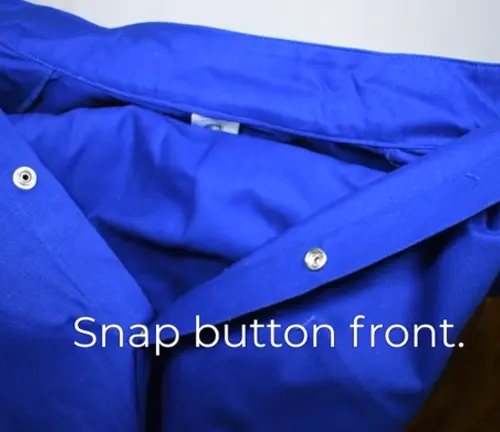Detail of the snap button front closure on a blue welding coat with text overlay 'Snap button front.'
