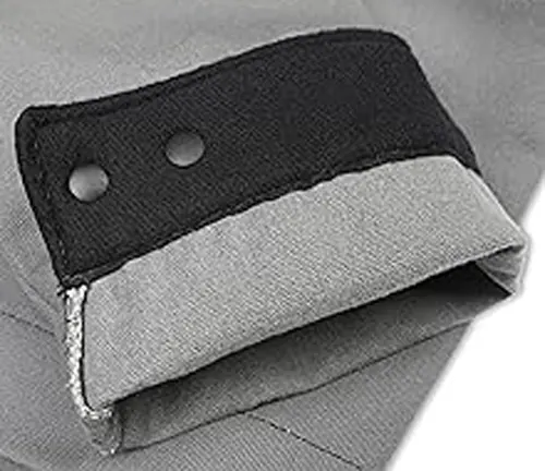 Close-up of a folded cuff on a Lincoln Electric XVI Series welding jacket, showing black and grey fabric with snap buttons.