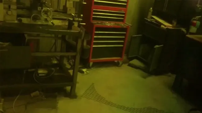 Dimly lit workshop with a red tool cabinet and various equipment on workbenches."











