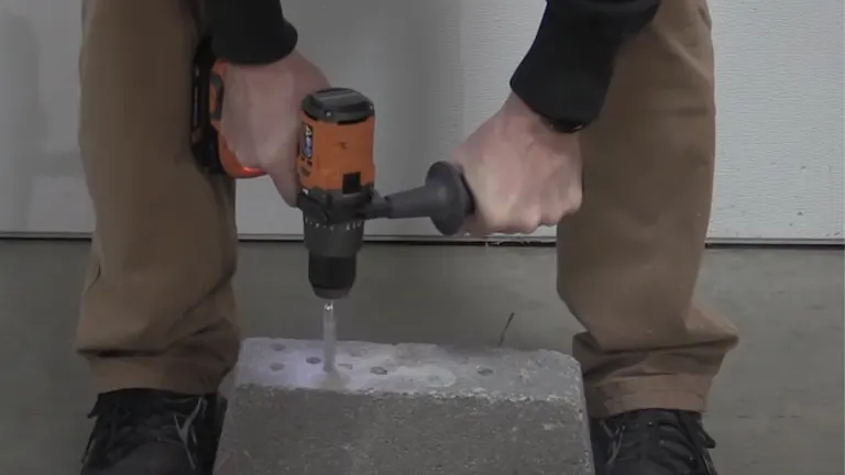 A person using a RIDGID cordless hammer drill on a concrete block, illustrating the tool's masonry drilling capability.