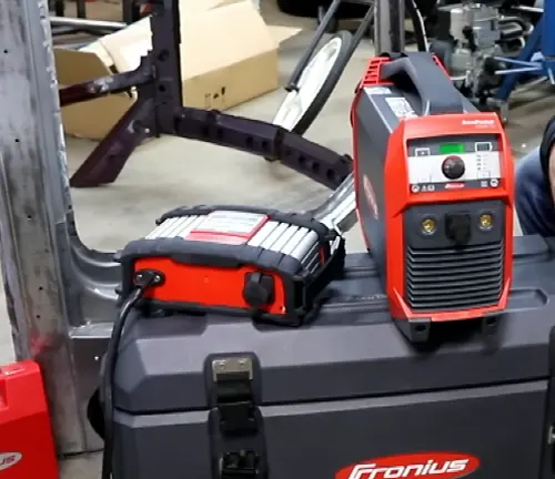 Fronius AccuPocket 150 TIG/Stick Welder set up on a toolbox in a workshop, with other welding gear in the background.






