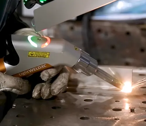 Close-up of a gloved hand operating a LightWELD 1500 Handheld Laser Welder with a bright welding spot on metal.