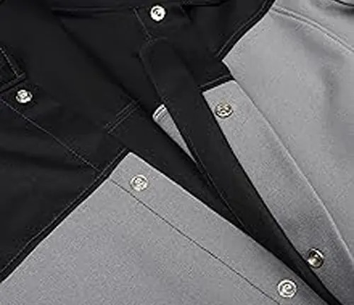 Detail of a Lincoln Electric XVI Series Industrial Welding Jacket, showcasing the black and grey panels with snap fasteners.