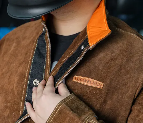 Close-up of a person wearing a YESWELDER heavy-duty flame-retardant welding jacket with the brand patch visible.





