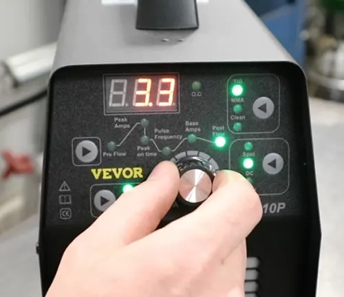 Close-up of a hand adjusting the settings on a VEVOR TIG Welder with a digital display reading 8.8.