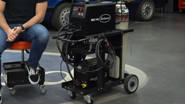 Fully equipped Eastwood welding cart in a workshop environment with a welder and tools on it.