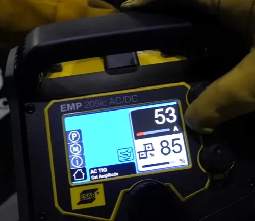 Illuminated display of the Esab Rebel EMP 205IC AC/DC Multi-Process Welder showing current settings, held by a person in welding gloves.