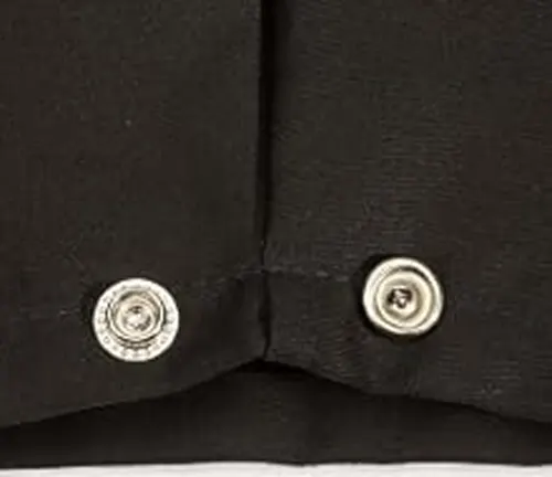 Close-up view of silver snap buttons on a black flame-resistant cloth welding jacket.