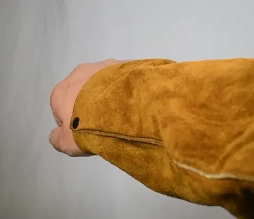 Side view of a cowhide sleeve on a welding coat with sown seam and snap button at the wrist.