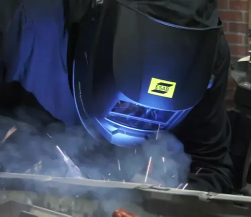 Welder using an ESAB Savage A40 Air helmet, with visible blue light from welding activity.