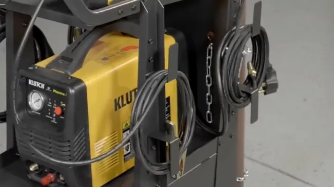 Close-up of a Klutch welding cart with a yellow welder and cables secured on the side.