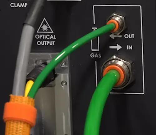 Close-up of the gas and optical output connections on a LightWELD 1500 Laser Welder with green and orange cables.