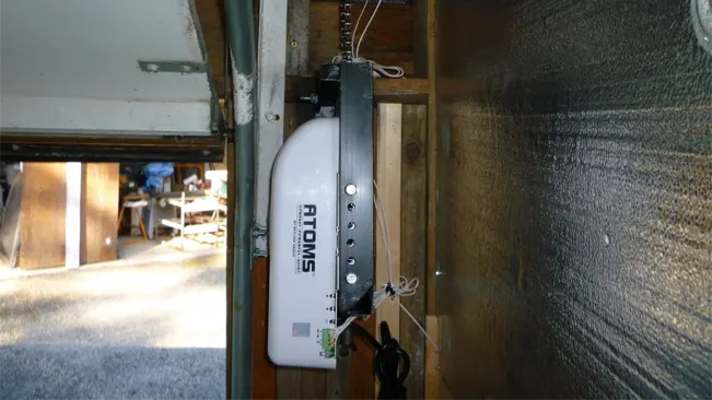 ATOMS garage door opener installed on the side of a garage opening, with a visible chain drive and a partial view of the interior.