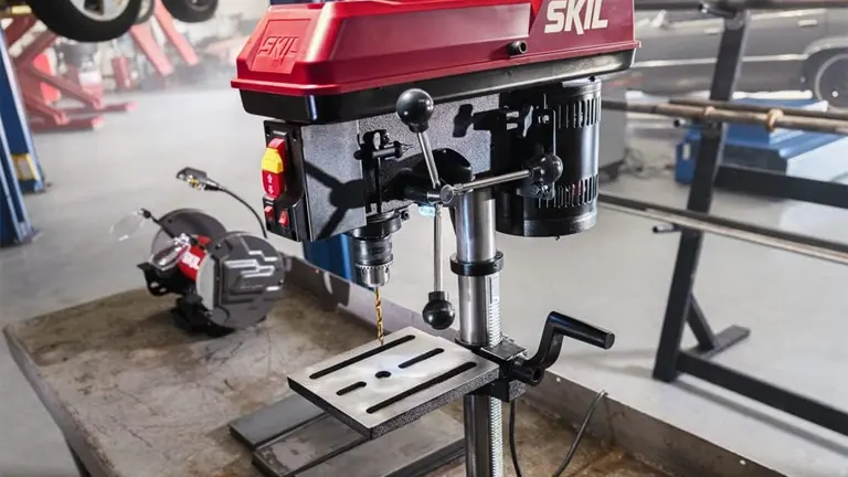 SKIL drill press with chuck and bit on a steel workbench, miter saw in the background