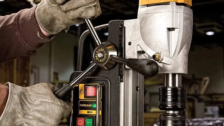 Close-up of a gloved hand adjusting the controls on a DEWALT drill press in an industrial setting