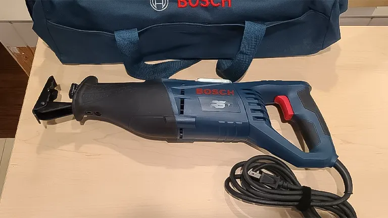 Bosch corded reciprocating saw on a wooden surface next to its carrying bag