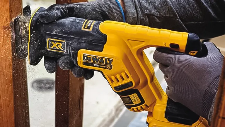 Person using a yellow and black DEWALT reciprocating saw on wood