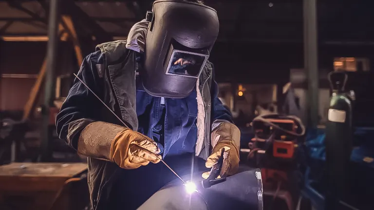 A welder using a TIG welding machine on metalwork