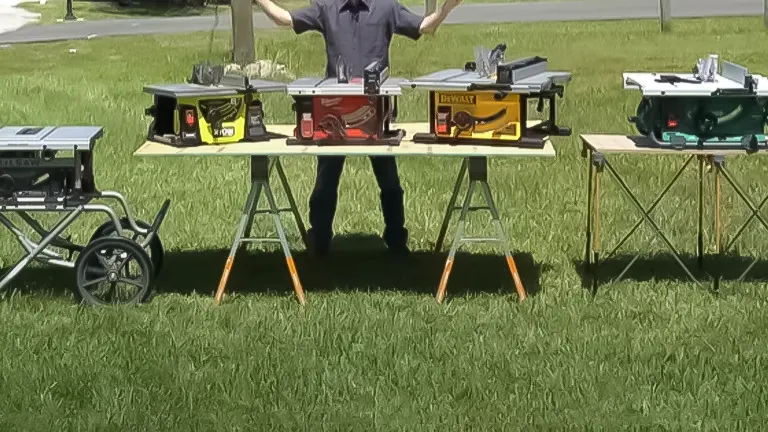 A person with arms raised behind a table showcasing five table saws outdoors