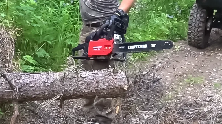 Person cutting a log with a CRAFTSMAN chainsaw, with off-road vehicle in the background