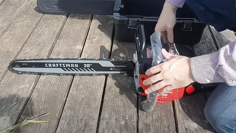 Person preparing a CRAFTSMAN 20" chainsaw next to an open toolbox on a wooden surface