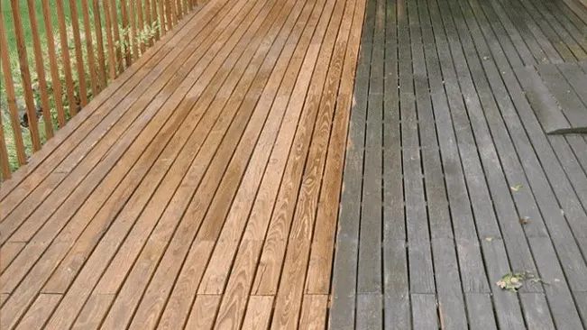 Partially cleaned wooden deck showing a clear line between the dirty and cleaned areas, demonstrating preparation for pressure washing.