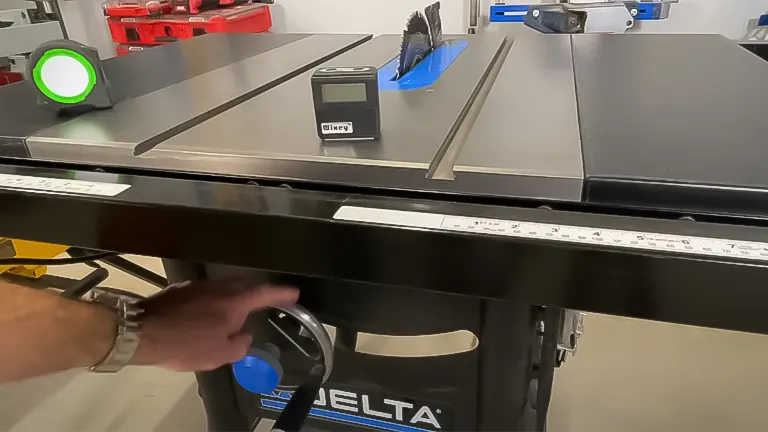 Person adjusting the fence on a Delta 36-6013 10 Inch Table Saw with measurement tape and blade guard visible