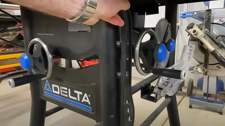 Person adjusting the blade height on a Delta 36-6013 10 Inch Table Saw, showcasing the bevel adjustment wheel and stand