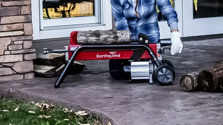Person operating a red and black Earthquake W500 Electric Log Splitter on a driveway