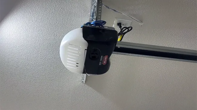 A black and white Genie garage door opener, with a chain drive mechanism, secured to the ceiling by a metal support.