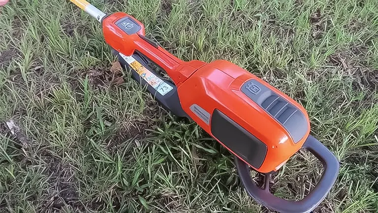 Husqvarna electric pole saw lying on grass