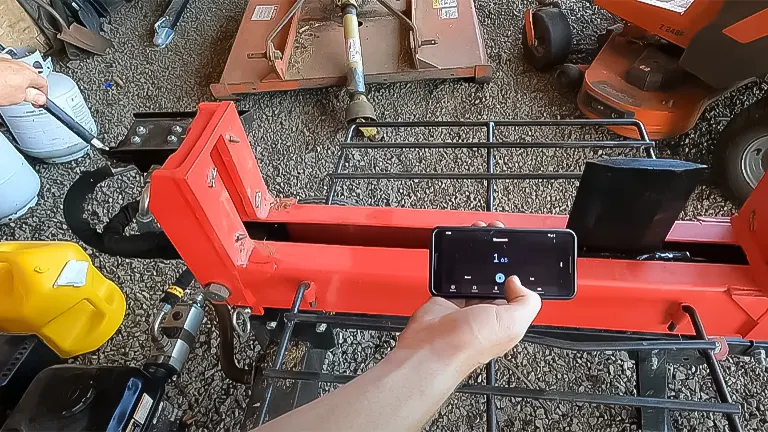 Person measuring log splitter with a smartphone app