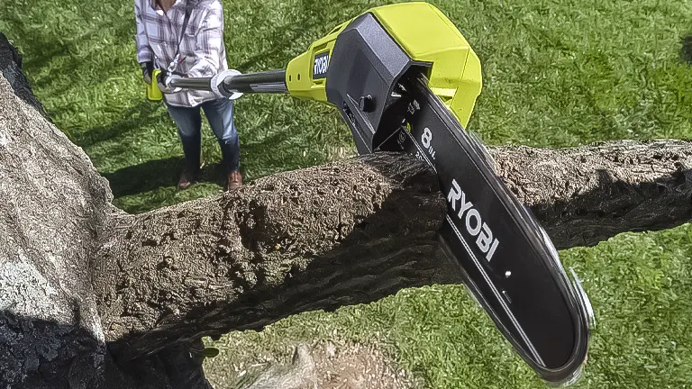 Person using a RYOBI ONE+ 18V 8-inch cordless pole saw on a thick branch