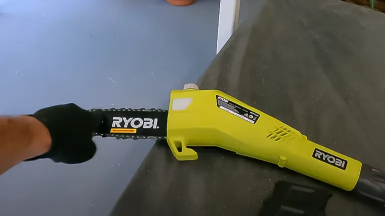 Person holding a RYOBI ONE+ 18V 8-inch cordless pole saw, with a focus on the saw head and chain