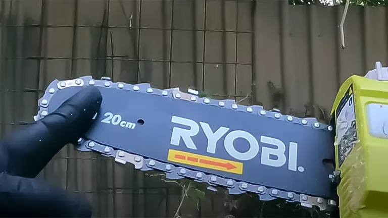 Close-up of a gloved hand pointing to the blade of a RYOBI 20 cm cordless pole saw