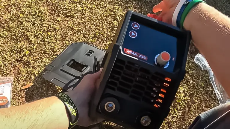 Person holding a Rubik ARC MMA 225Amp handheld electric stick welder with a visible control screen