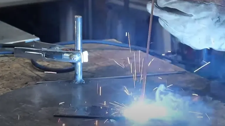Welding process in action with sparks flying, using a clamp and electrode rod