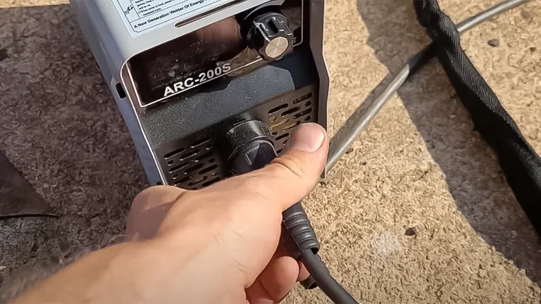 Close-up of a hand plugging a connector into the SSIMDER Mini ARC200S welder