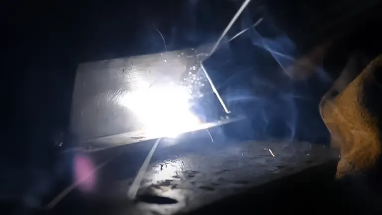 Intense welding arc and sparks on a metal surface in a dimly lit setting