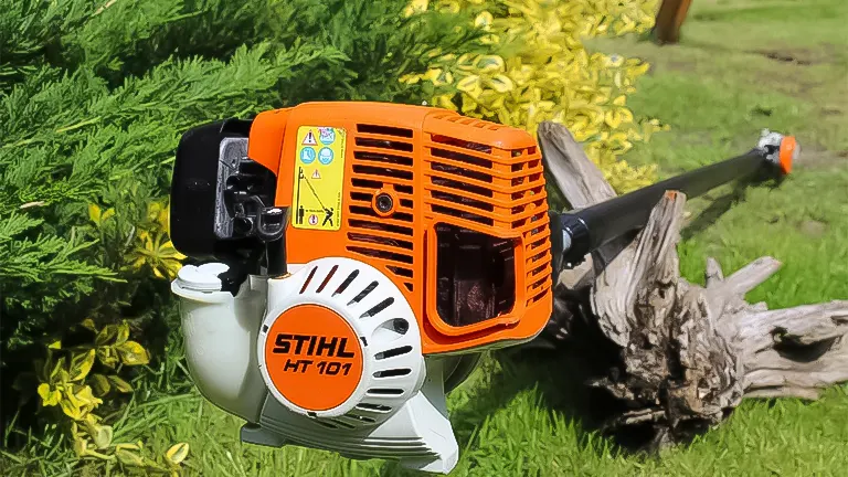 STIHL HT 101 pole saw with visible controls and fuel tank, set against garden foliage