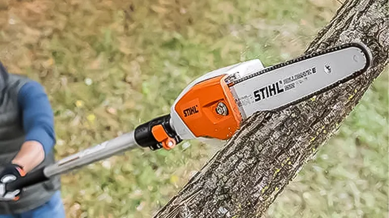 Close-up of a STIHL HT 101 pole saw cutting a tree branch, with focus on the saw head and blade