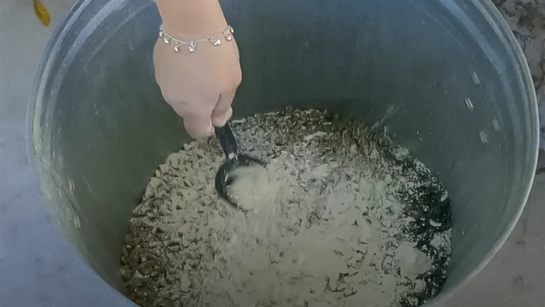 A hand scooping mixed chicken feed from a large bin