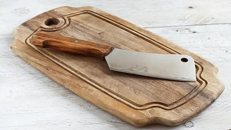 A handmade wooden cutting board with an elongated shape, accompanied by a cleaver resting
